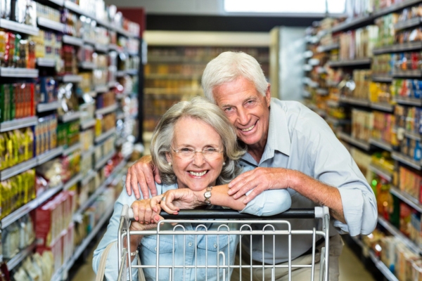 smiling senior couple with grocery cart