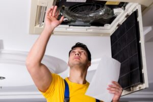 professional HVAC technician examining central air conditioner system