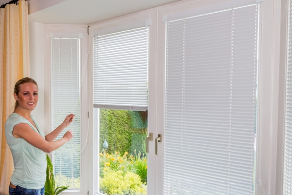 woman putting window blinds down to block sunlight