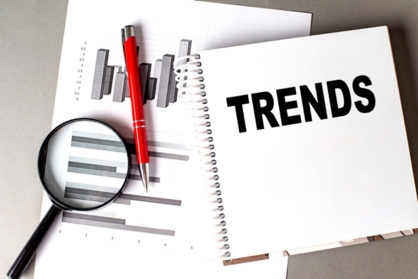 chart reports, pen, magnifying glass, and notebook with trends written on it depicting future AC trends