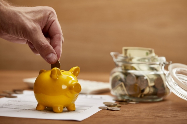 homeowner dropping coins on golden piggy bank depicting energy saving strategies