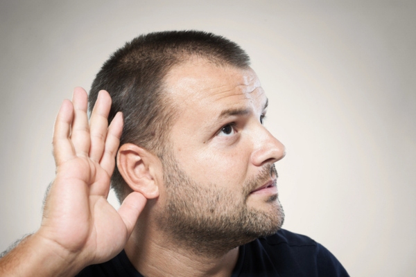 man holding hand on ear listening to air conditioner noise