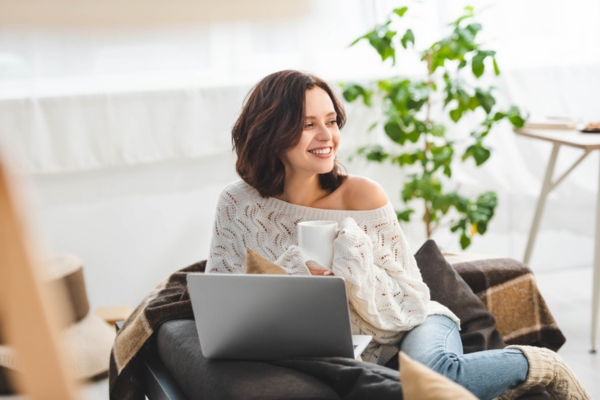 woman feeling warm and cozy while working at home with a cup of tea depicting reliable heat from heating oil