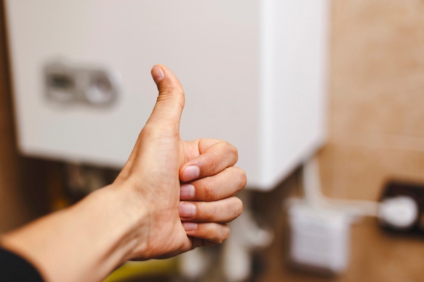 Homeowner near central heating boiler system doing a thumbs up depicting choosing the best boiler