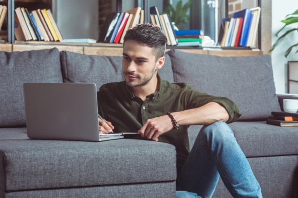 man with laptop and notebook checking out factors before buying a new furnace