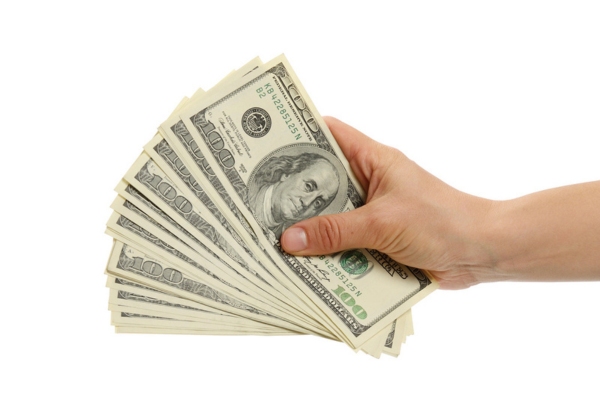 woman's hand holding a stack of 100 dollar bills depicting long-term financial gains from high heat pump efficiency