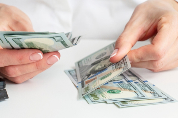 cropped view of a woman's hand counting money depicting fuel oil price fluctuation